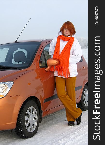 Red-haired girl and orange car on winter road