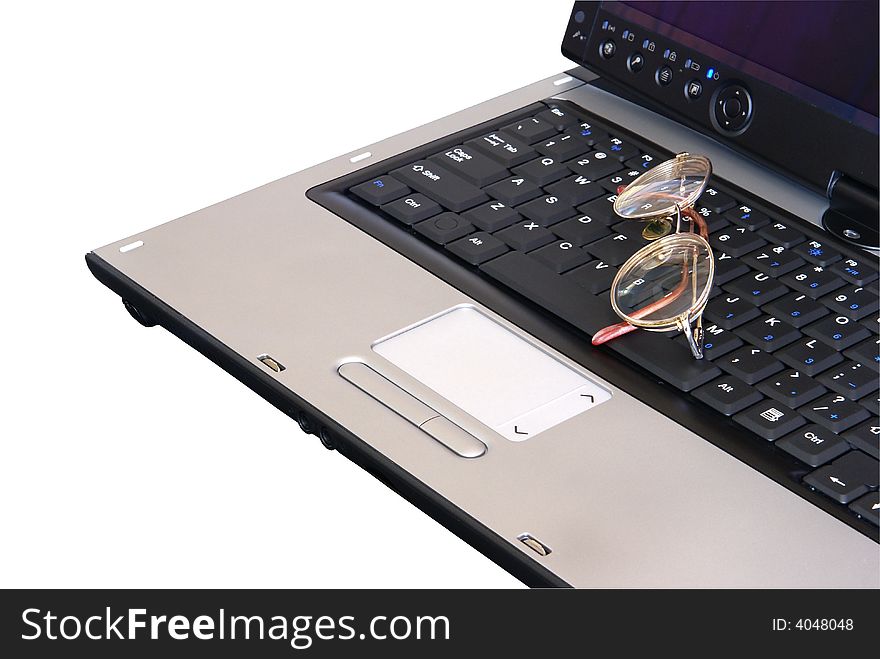 Laptop computer closeup with eyeglasses sitting on keyboard.