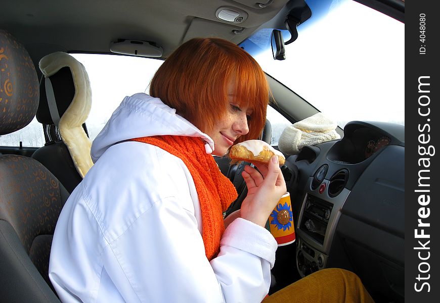 Red-haired girl with mug and sweet roll