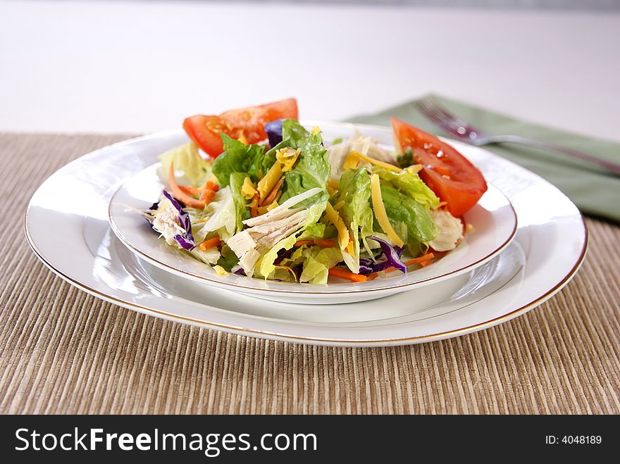 Healthy salad with lettuce, carrots, radish, cabbage, turkey, tomato wedges, and cheese