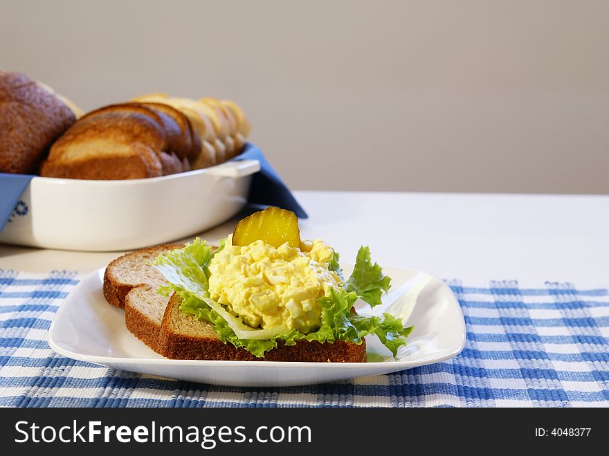 Egg Salad Sandwich on whole grain bread with pickles.