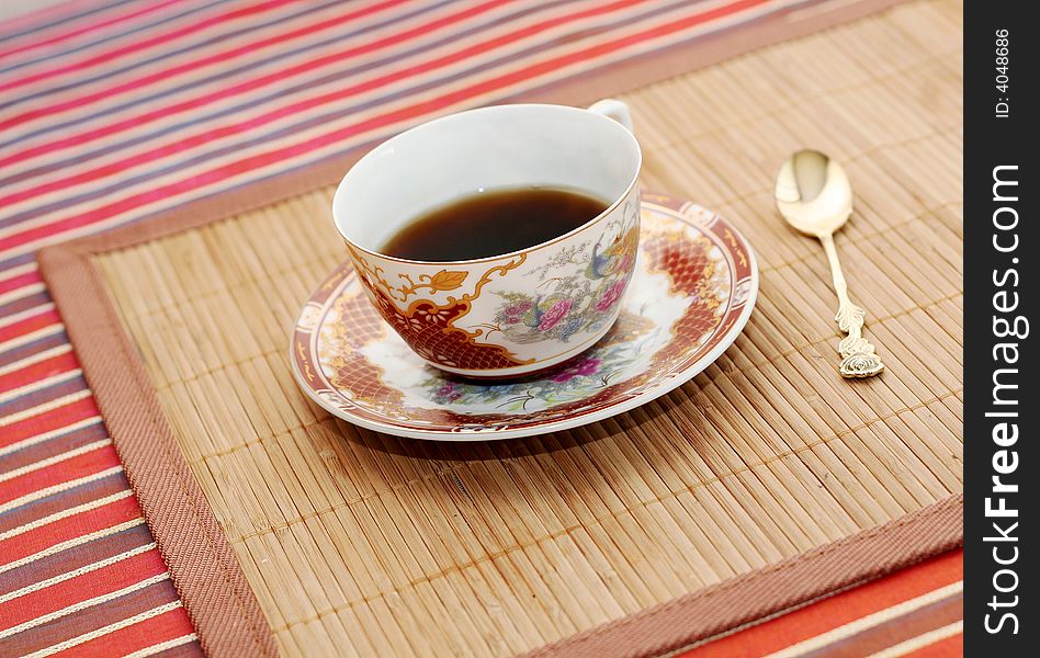 Chinese cup of coffee and gold spoon on bambo tray