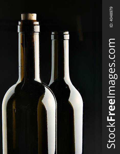 Necks of two bottles over black background