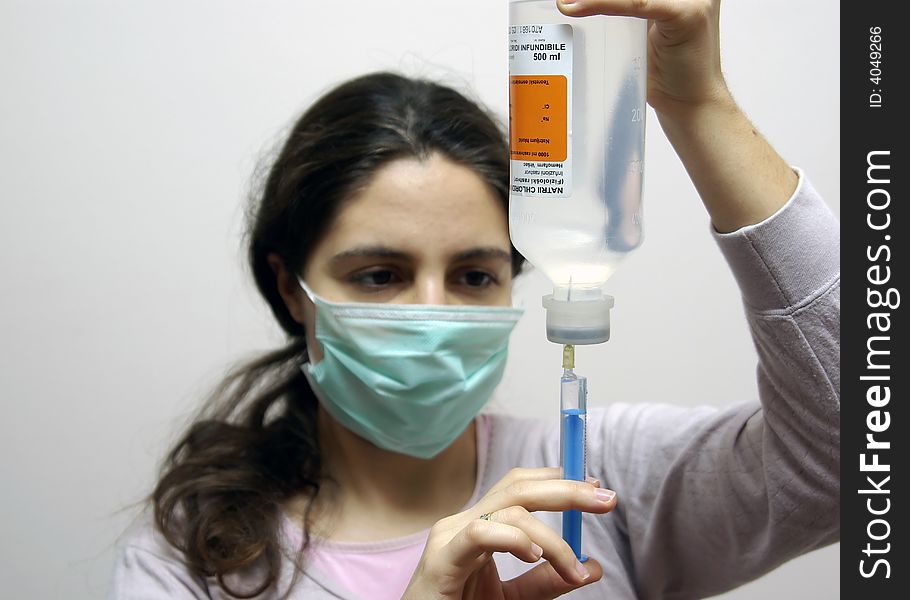 A girl, preparing the injection, wearing a mask. A girl, preparing the injection, wearing a mask