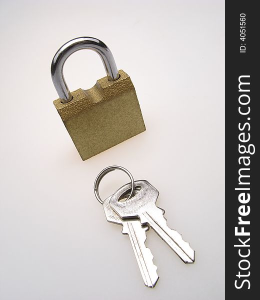 Closed hinged lock with keys laying by  line on  light background. Closed hinged lock with keys laying by  line on  light background