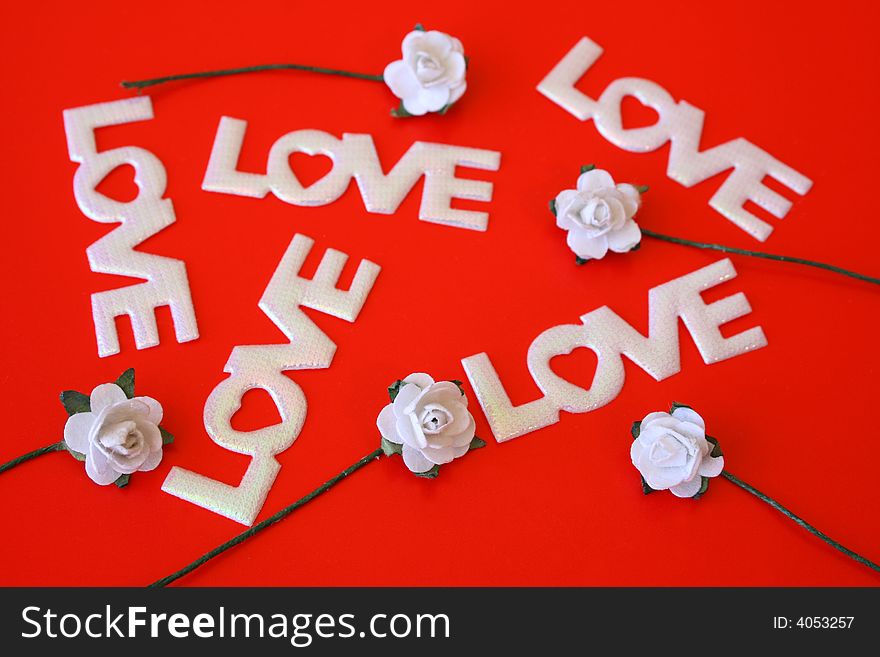 The word love on a red background with small white roses. The word love on a red background with small white roses