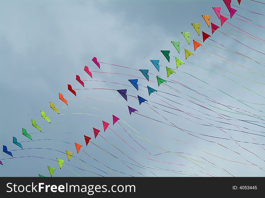 Four strings of colourful stunt kites with long tails on a cloudy sky background. Four strings of colourful stunt kites with long tails on a cloudy sky background