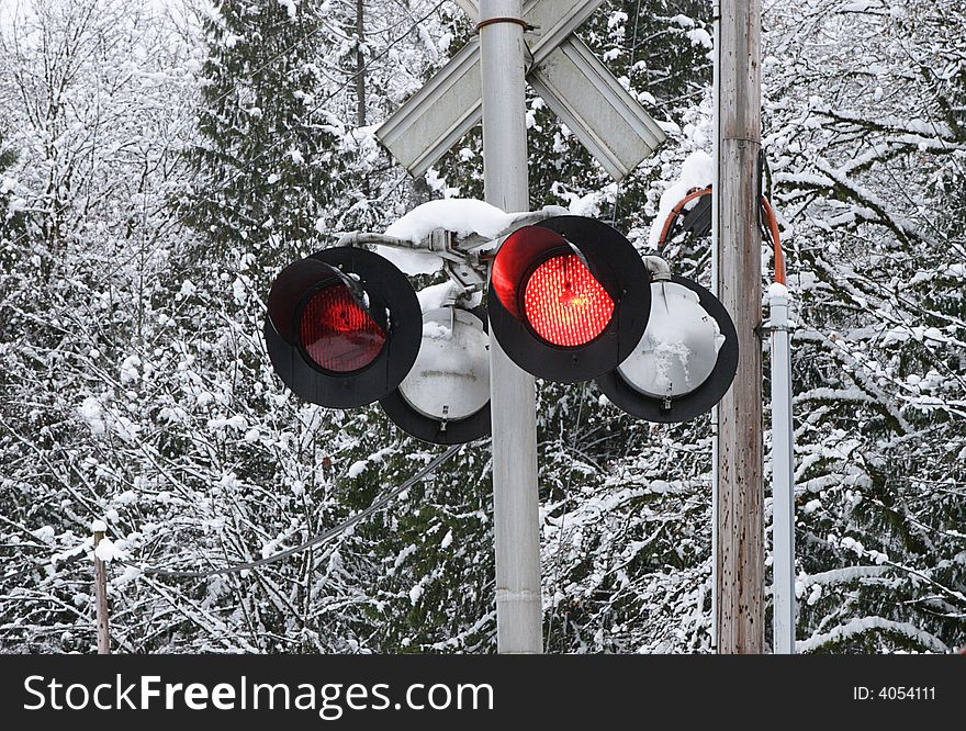 Flashing railroad warning light at a snowy railroad crossing. Flashing railroad warning light at a snowy railroad crossing