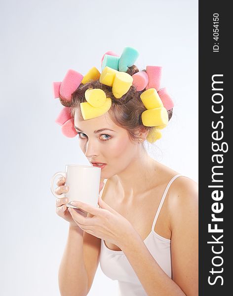 A woman in hair curlers with a cup. A woman in hair curlers with a cup