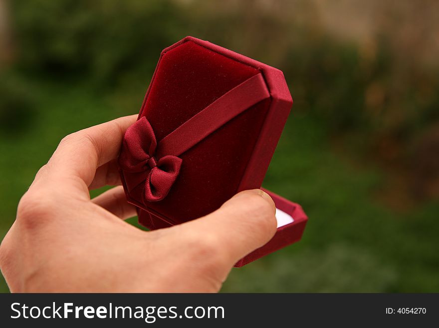 A red gift box with a bow held in hand