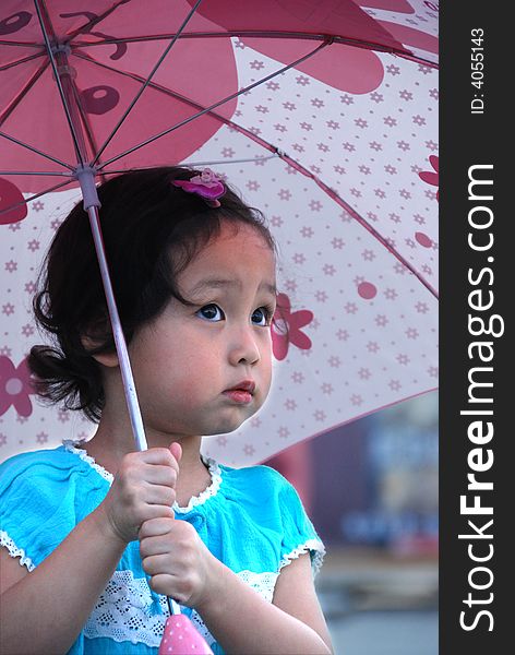 Cute beautiful Chinese young child under umbrella in summer