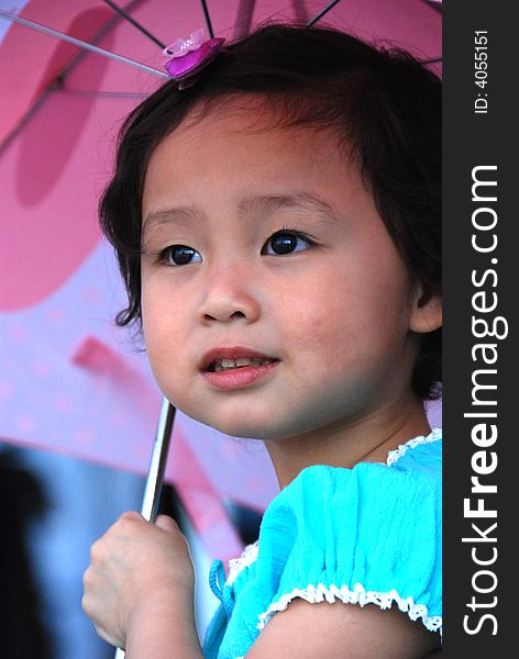 Cute beautiful Chinese young child under umbrella in summer