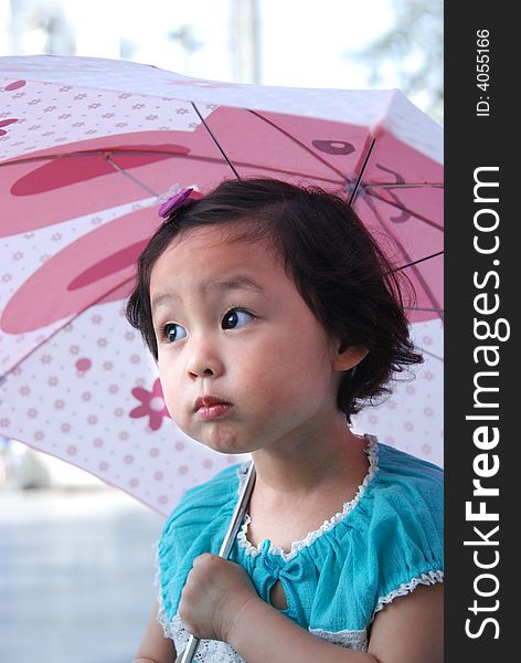 Cute beautiful Chinese young child under umbrella in summer