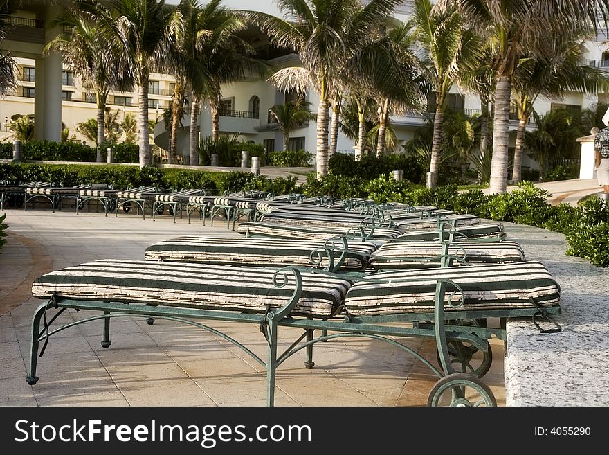 Rows of green and white chaise lounges around a seaside pool