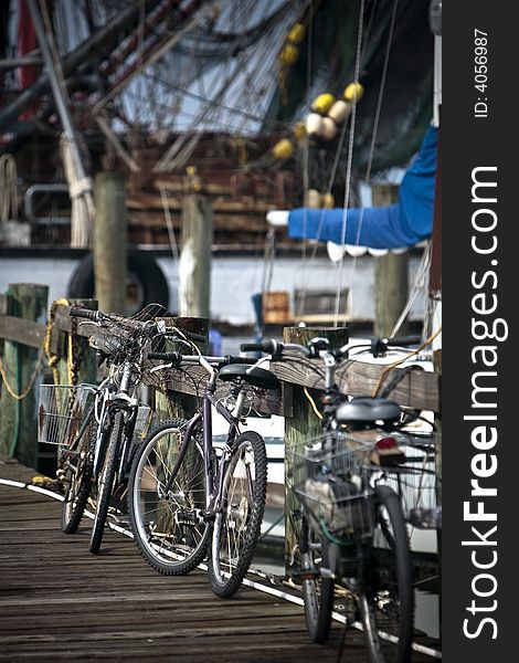 Bikes, leaning on a railing of a dock where a shrimp boat has just arrived,. Bikes, leaning on a railing of a dock where a shrimp boat has just arrived,