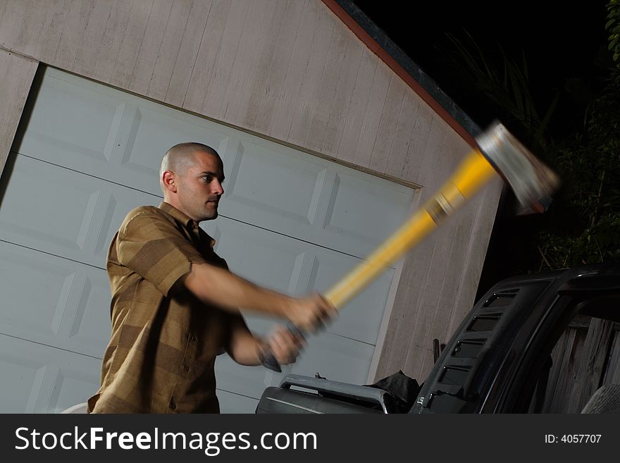 Man chopping a vehicle at night. Can be used to depict a robber trying to break into someones vehicle