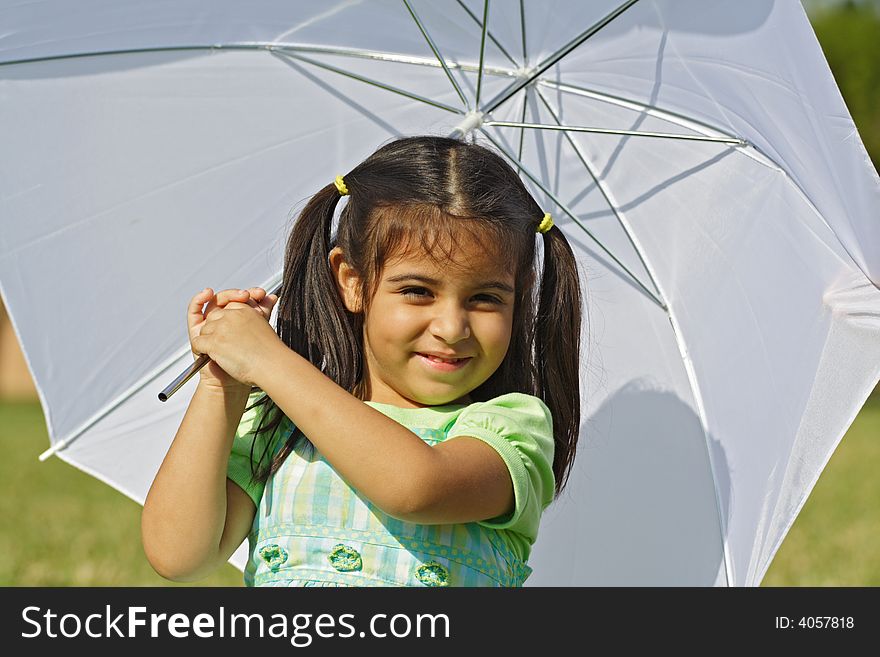 Girl underneath an umbrella with green grass background. Girl underneath an umbrella with green grass background