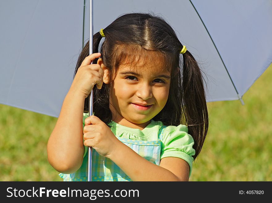 Girl underneath an umbrella with green grass background. Girl underneath an umbrella with green grass background