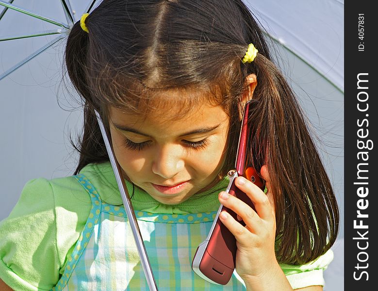 Girl talking on a cell phone under a white umbrella. Girl talking on a cell phone under a white umbrella