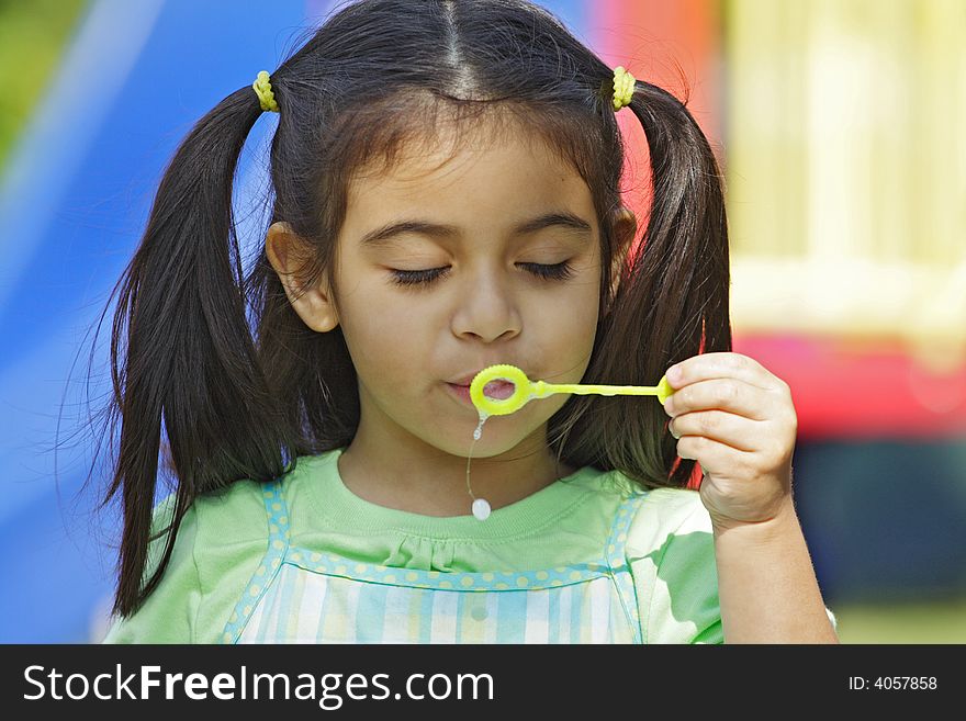 Little Girl blowing bubbles with eyes closed