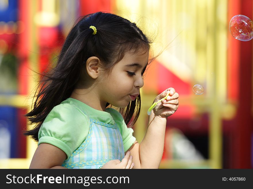 Little Girl blowing bubbles at the playground