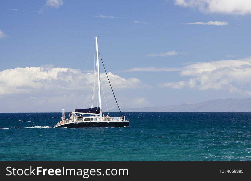 A catamaran motors over a turquoise sea on a sunny day. A catamaran motors over a turquoise sea on a sunny day.