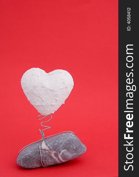A white heart on a stone base on red background