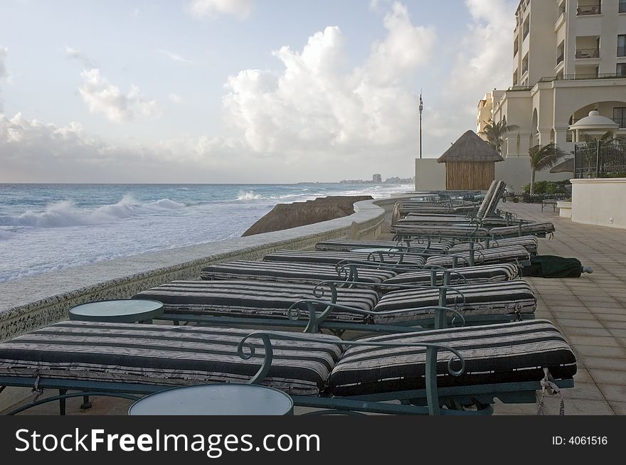 A row of lounge chairs on top of a sea wall at the beach. A row of lounge chairs on top of a sea wall at the beach