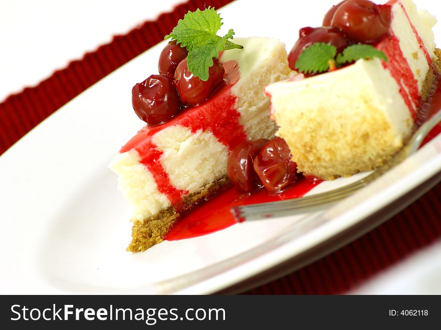 New York style cheese cake slices with rich cherry sauce topping and mint (lemon balm) leaf garnish. New York style cheese cake slices with rich cherry sauce topping and mint (lemon balm) leaf garnish.