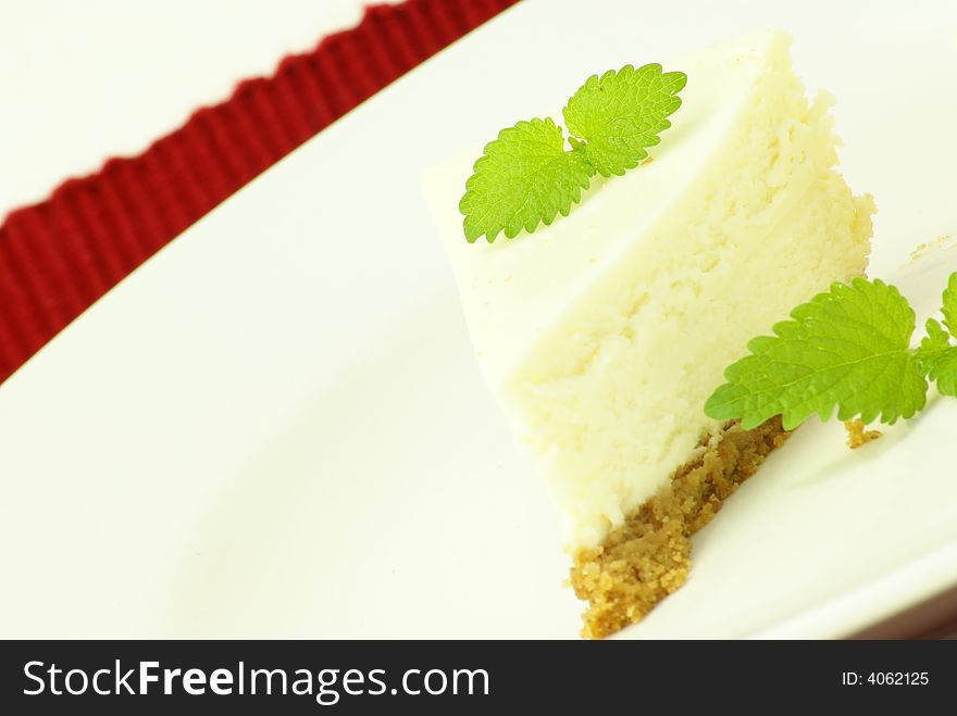 Plain New York style cheesecake slice with garnish of lemon balm (mint) leaves. Plain New York style cheesecake slice with garnish of lemon balm (mint) leaves.