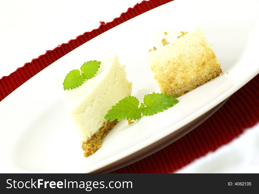 Plain New York style cheesecake slice with garnish of lemon balm (mint) leaves. Plain New York style cheesecake slice with garnish of lemon balm (mint) leaves.