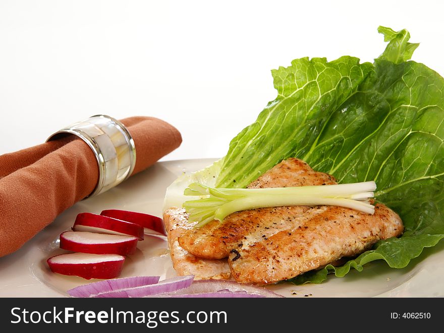 Cooked pink salmon with lettuce leaf, onions, and radish.