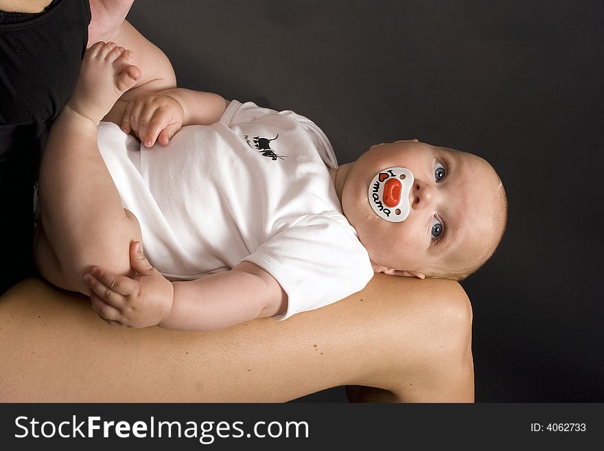 A baby that is lying on his mothers leggs. A baby that is lying on his mothers leggs