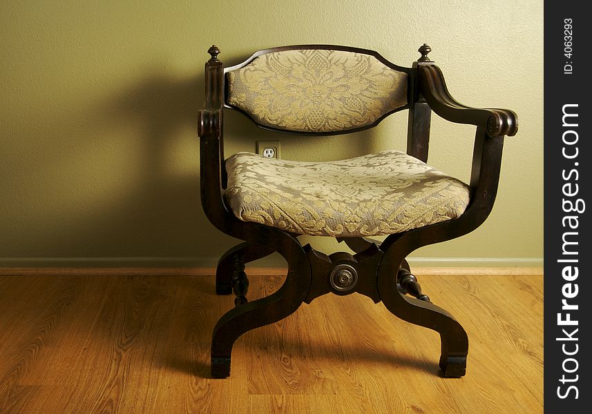 Ornate Roman Styled Chair Against an Olive Green Wall