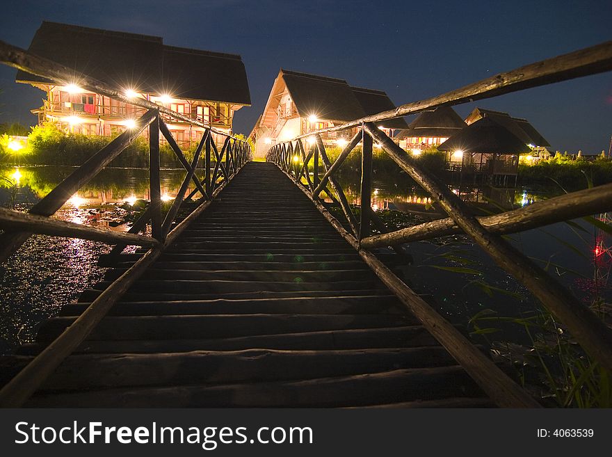 A view looking upwards over a long outdoor stairway toward several well-lit buildings at night. A view looking upwards over a long outdoor stairway toward several well-lit buildings at night.