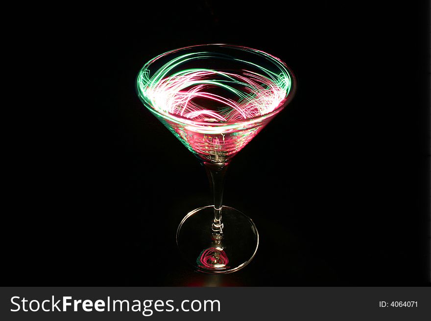 Cocktail glass with coloured light trails on a black background. Cocktail glass with coloured light trails on a black background