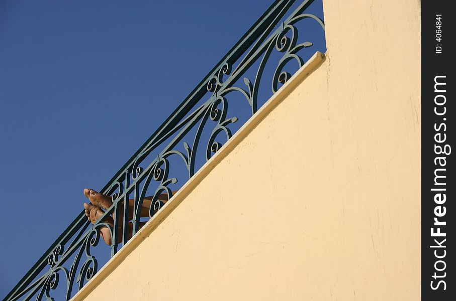 Feet Resting On Decorative Wrought Iron Railing