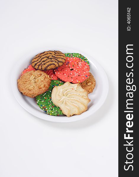Assorted holiday cookies on a plate with semi-isolated white background and a vertical composition.