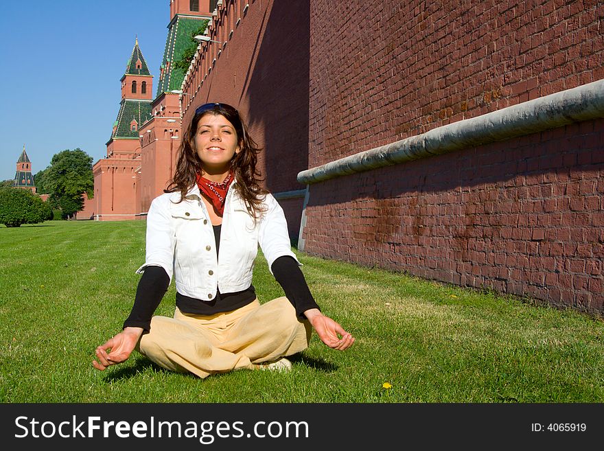 Pretty young woman meditate near Moscow Kremlin, sitting on a grass and smile. Pretty young woman meditate near Moscow Kremlin, sitting on a grass and smile