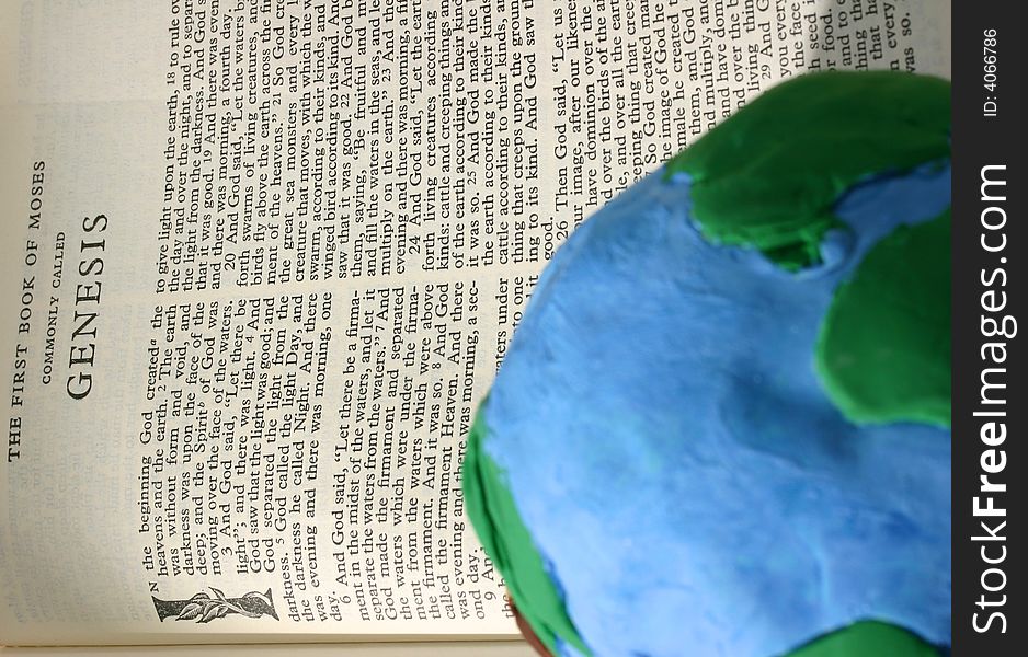 Crude earth globe sitting on an open Bible open to the book of Genesis. Crude earth globe sitting on an open Bible open to the book of Genesis