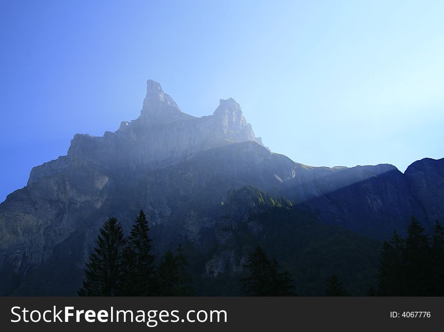 Sunlight streams over two alpine peaks. Sunlight streams over two alpine peaks