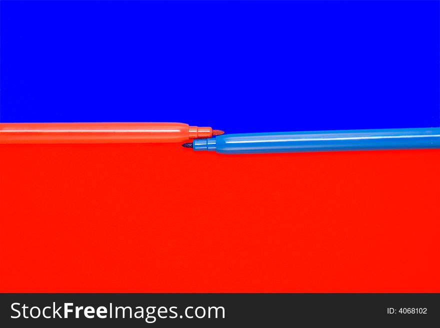 Red and blue felt-tip pens lay on a color background. Red and blue felt-tip pens lay on a color background