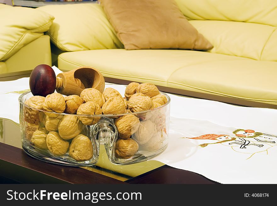 Walnuts with screw-cracker on table by sofa. Walnuts with screw-cracker on table by sofa