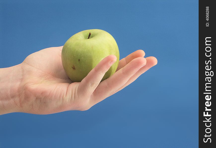 Hand to hold gpeen apple on blue background. Hand to hold gpeen apple on blue background