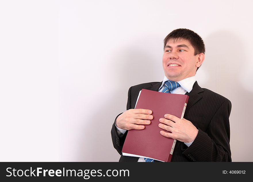 Man in a suit presses a folder with papers to a breast and smiles. Man in a suit presses a folder with papers to a breast and smiles.