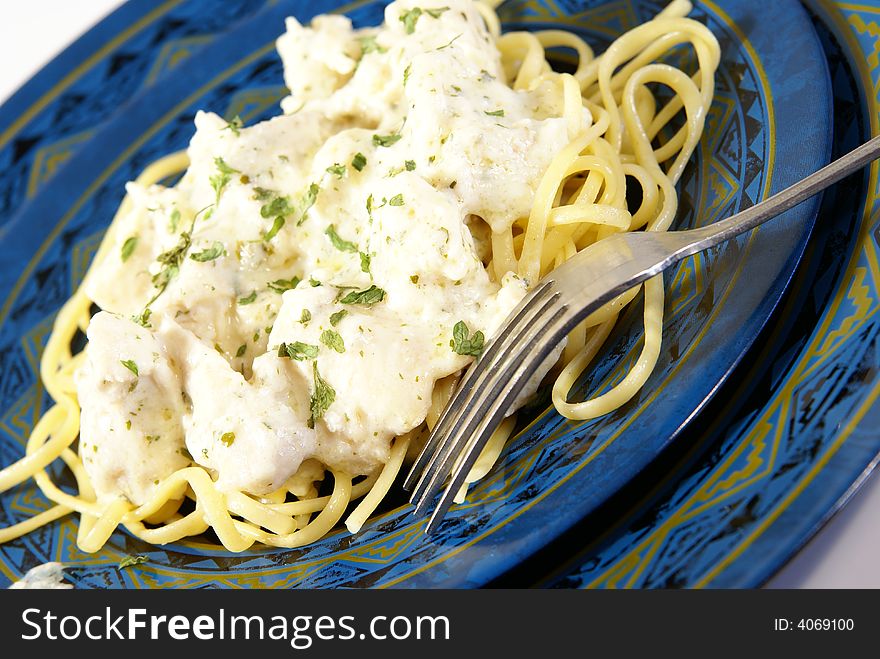 Chicken Alfredo. Sauce, chicken, and dried herbs on flat linguini pasta.