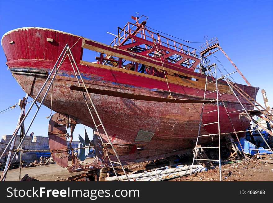 Morocco, Essaouira:repairing a  red and old fishing boat. Morocco, Essaouira:repairing a  red and old fishing boat