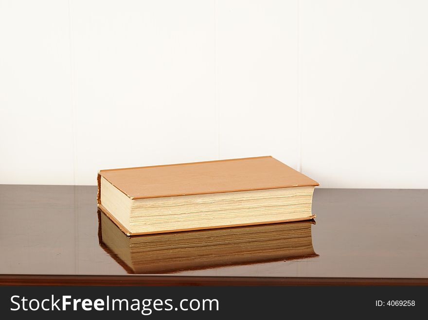 Old hardback books on polished dark cherry wood table. Old hardback books on polished dark cherry wood table