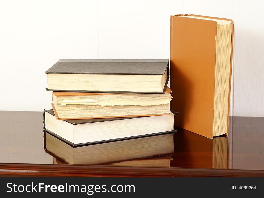 Old hardback books on polished dark cherry wood table. Old hardback books on polished dark cherry wood table