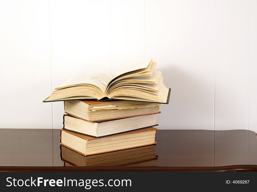 Old hardback books on polished dark cherry wood table. Old hardback books on polished dark cherry wood table